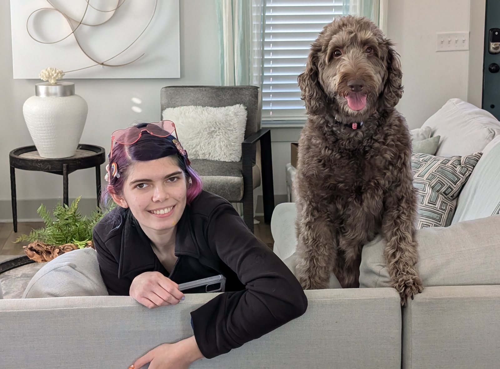 Elisabeth kneeling beside a large brown labradoodle in a living room.