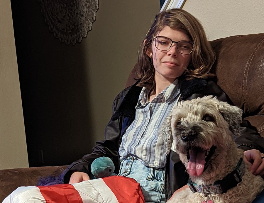 Elisabeth on the couch with a cream coloured doodle resting against her.